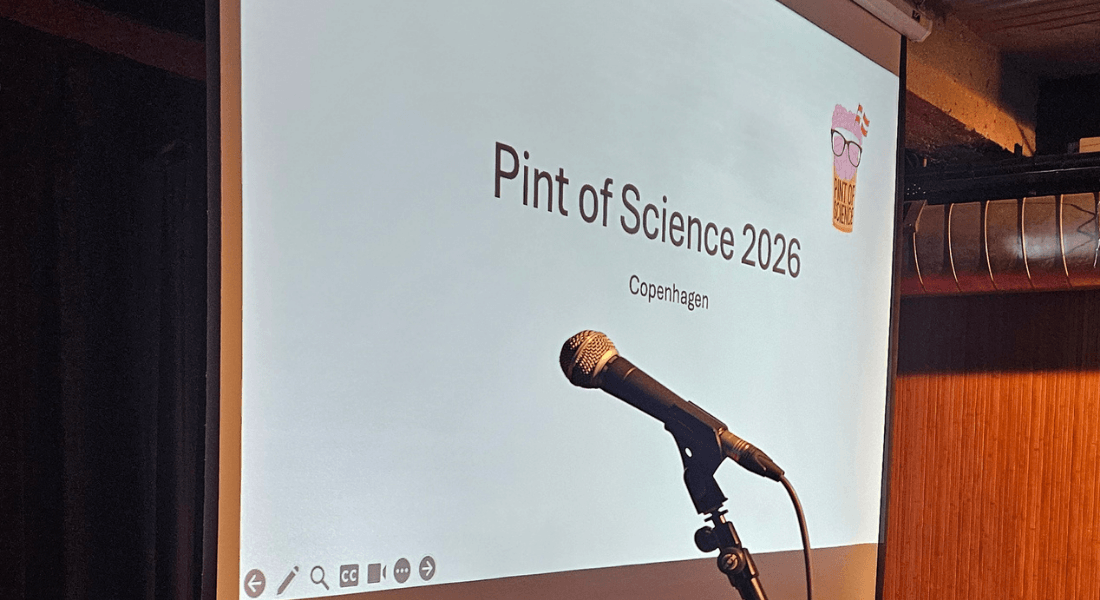 Microphone in front of a projector screen displaying "Pint of Science 2026, Copenhagen."